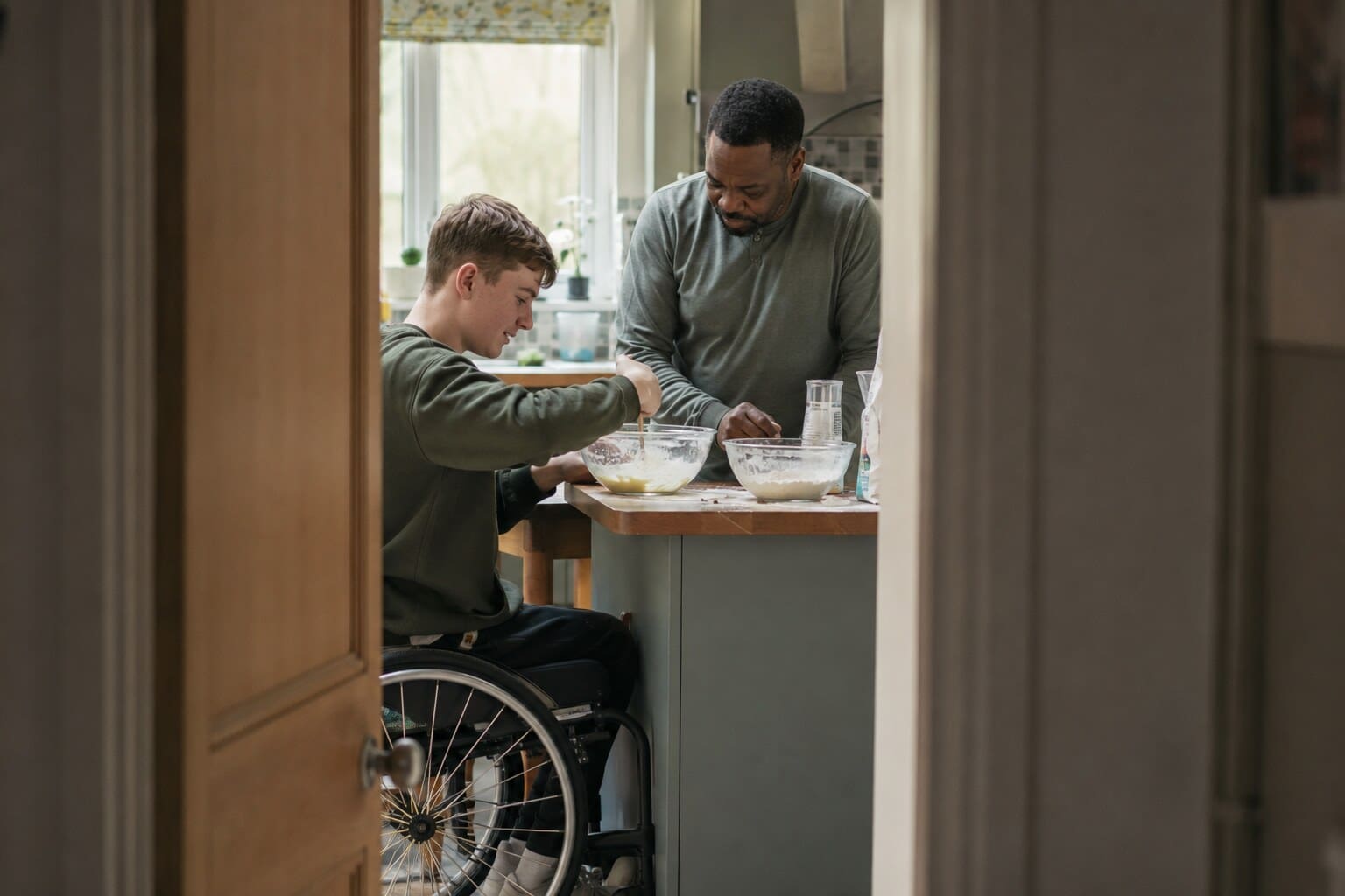 A foster carer and a child working through a picture chart together at the kitchen table.